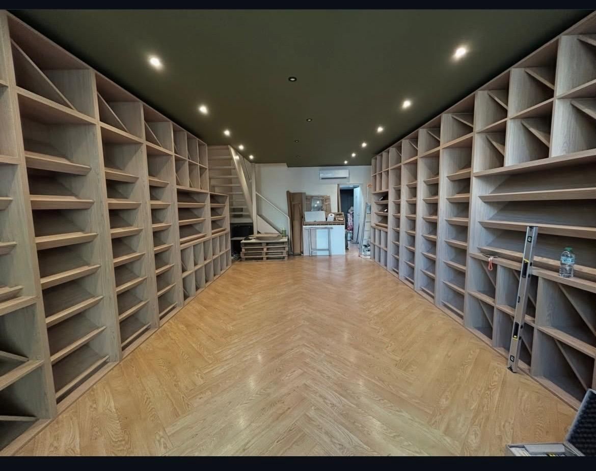 Longue salle d’archives aux rayonnages en bois, parquet posé en chevrons sur toute la longueur