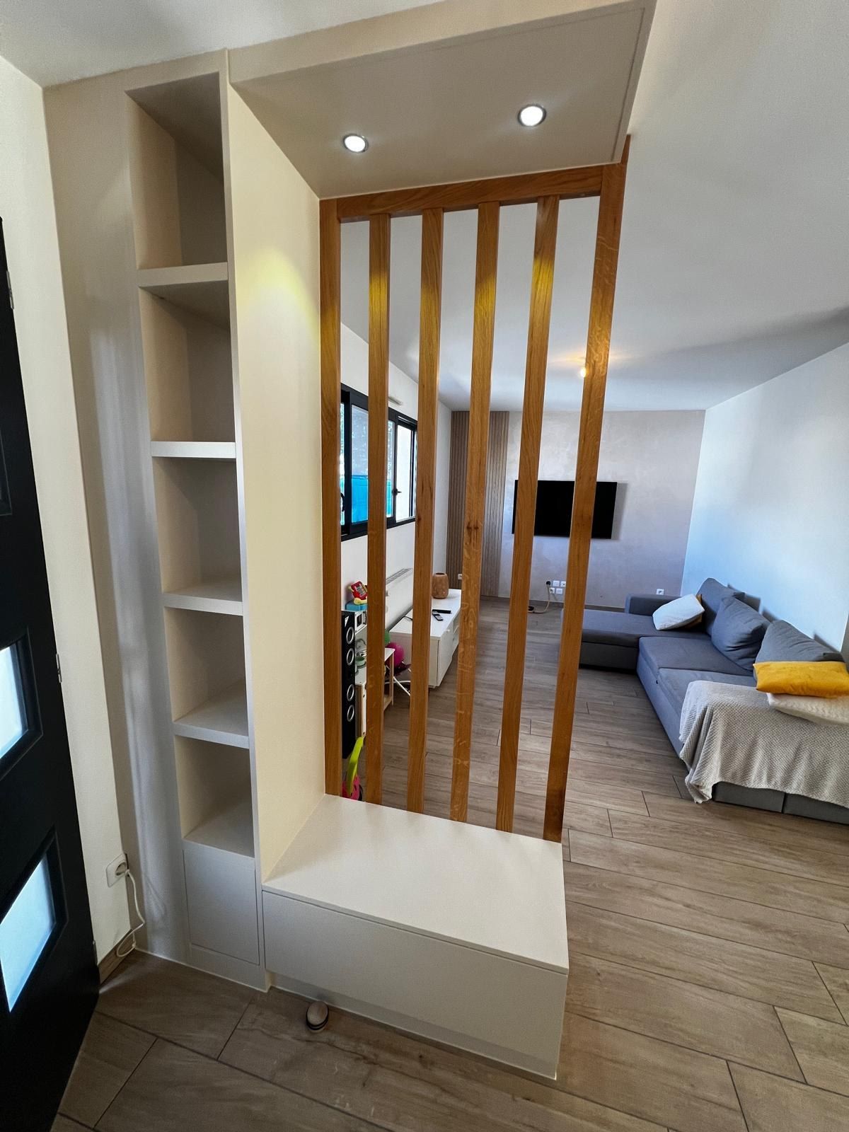 Claustra en bois et niches de rangement blanches séparant une pièce de nuit du séjour