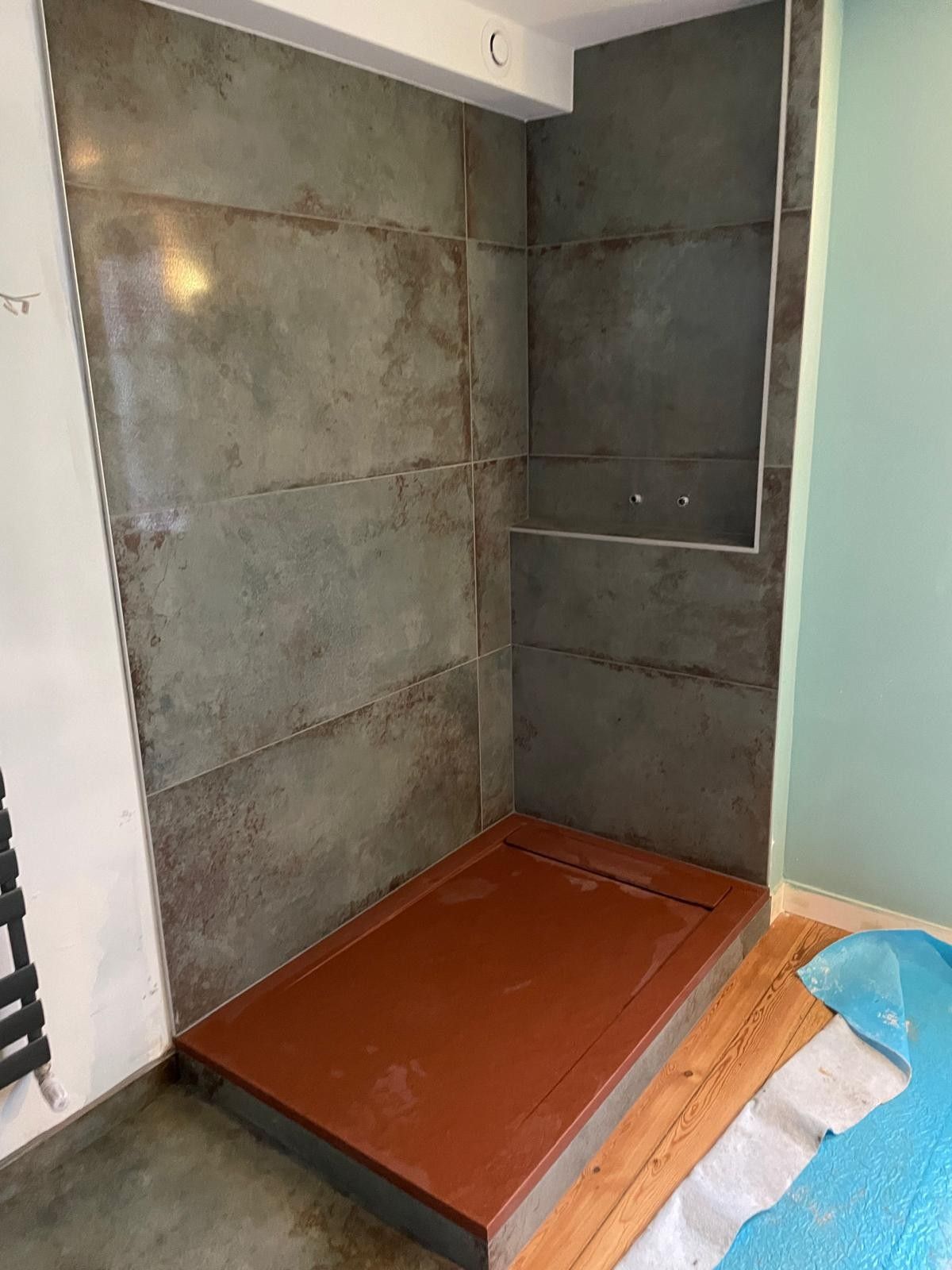 Douche en cours de carrelage avec de grandes dalles aspect métal oxydé