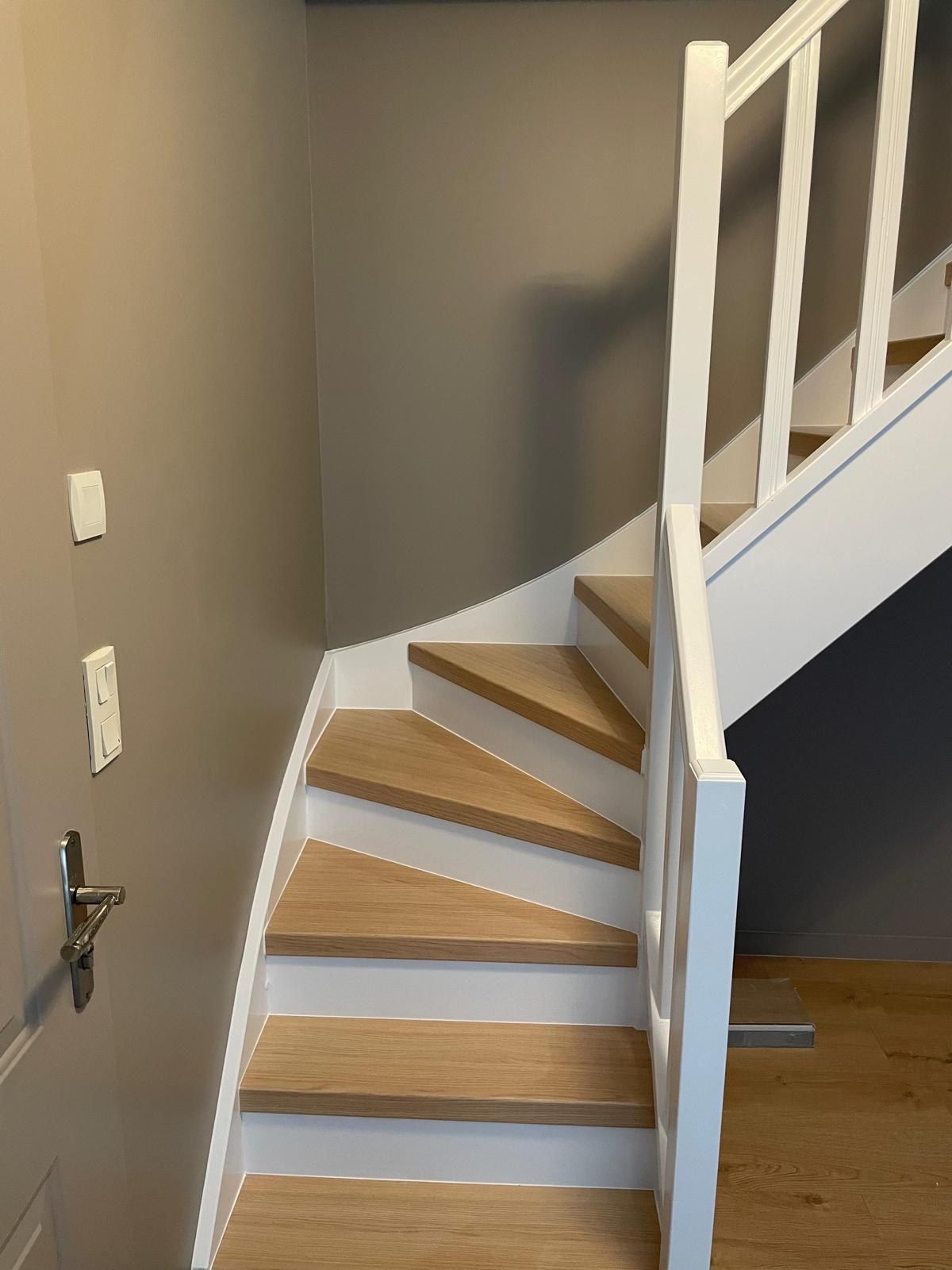Escalier quart tournant à marches en bois et limon blanc, devant un mur peint en gris