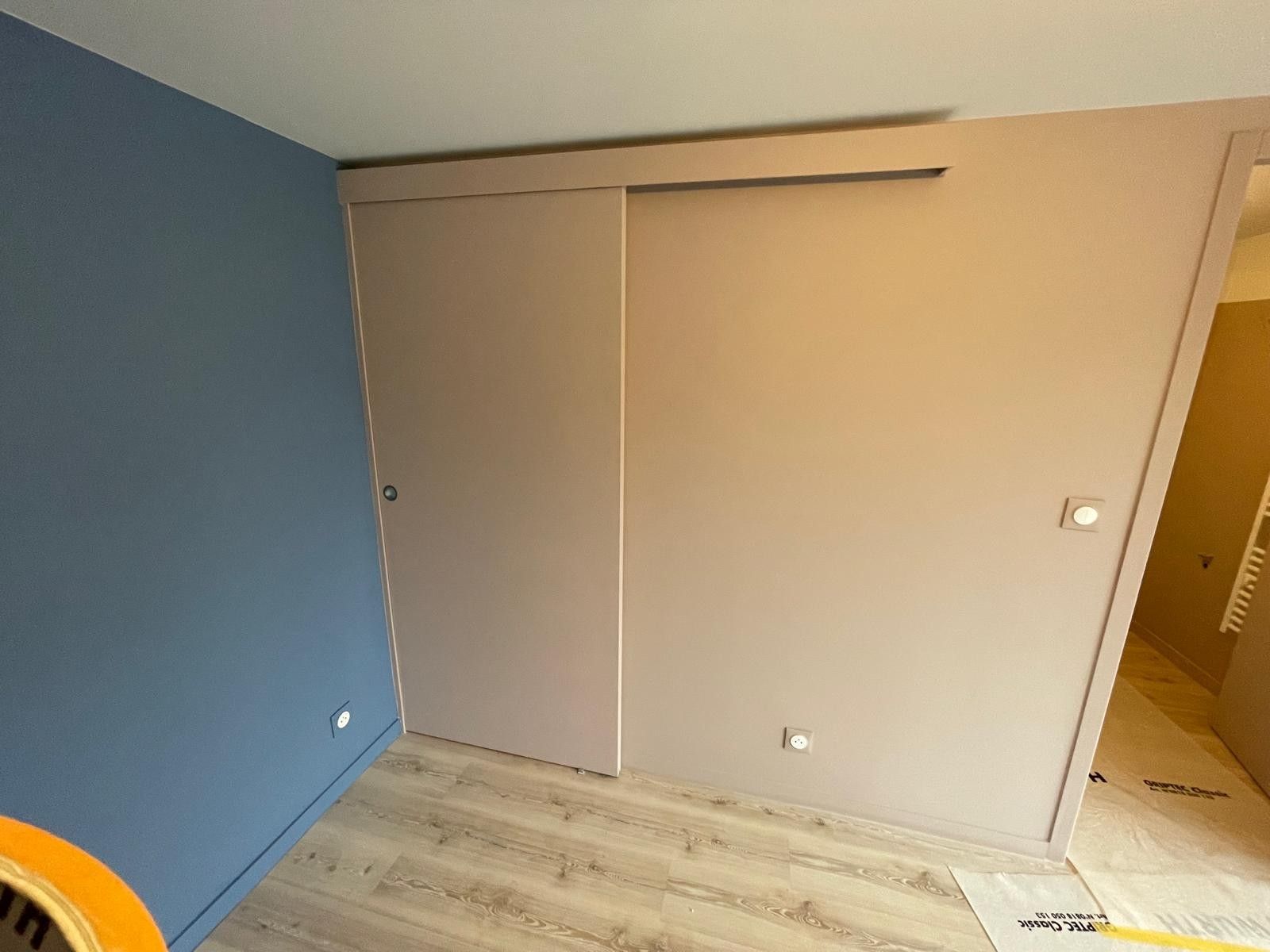 Pièce repeinte en bleu avec un placard à portes coulissantes beiges