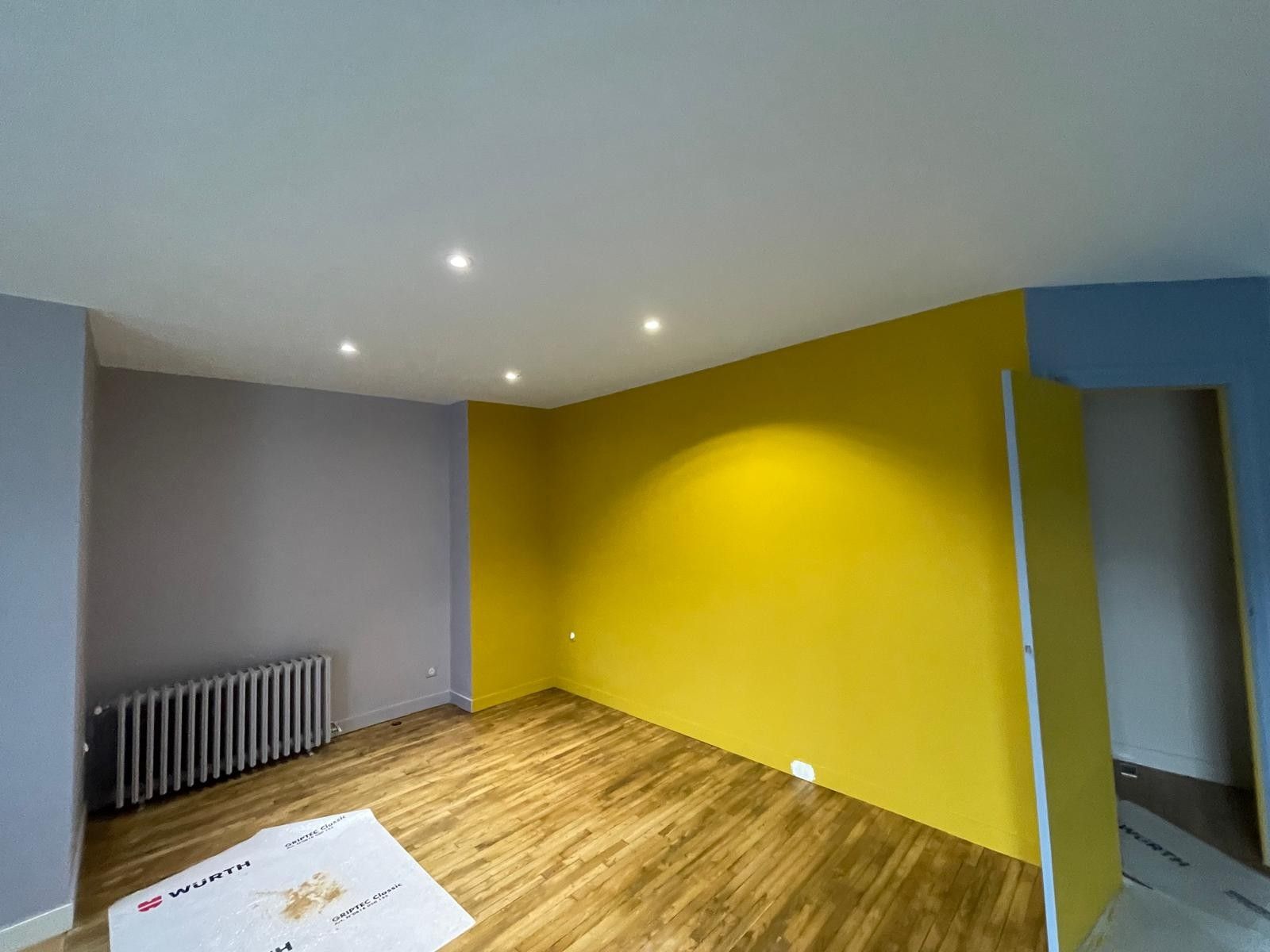 Pièce repeinte avec un mur jaune, un mur gris et un mur bleu
