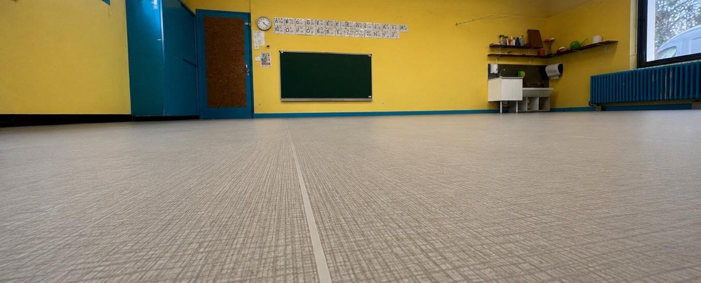 Grande salle aux murs jaunes et turquoise d’un local professionnel, avec un sol souple clair posé
